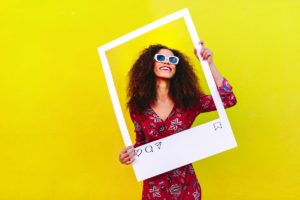 How to Repost Your Company’s Content to Amplify Your Brand and Business Connections - smiling woman with a yellow background - web