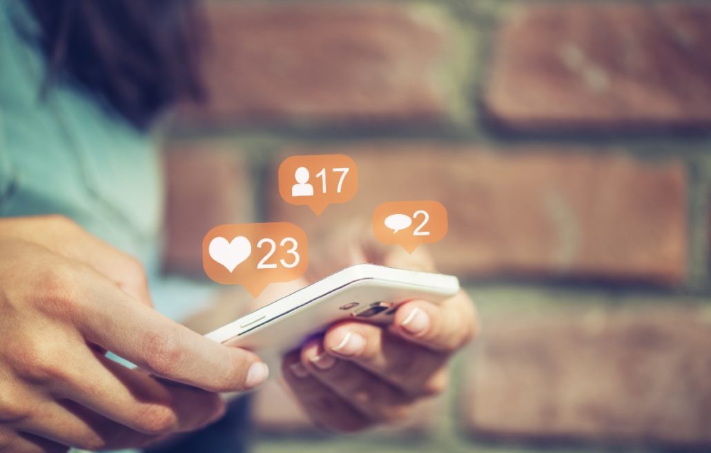 How to repost your companys content on social media girl using phone with hearts and likes